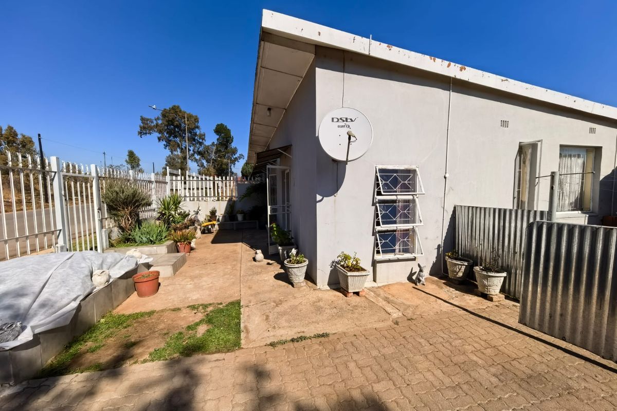Rear exterior view of the townhouse featuring a paved area, security fencing, and a satellite dish installation.
