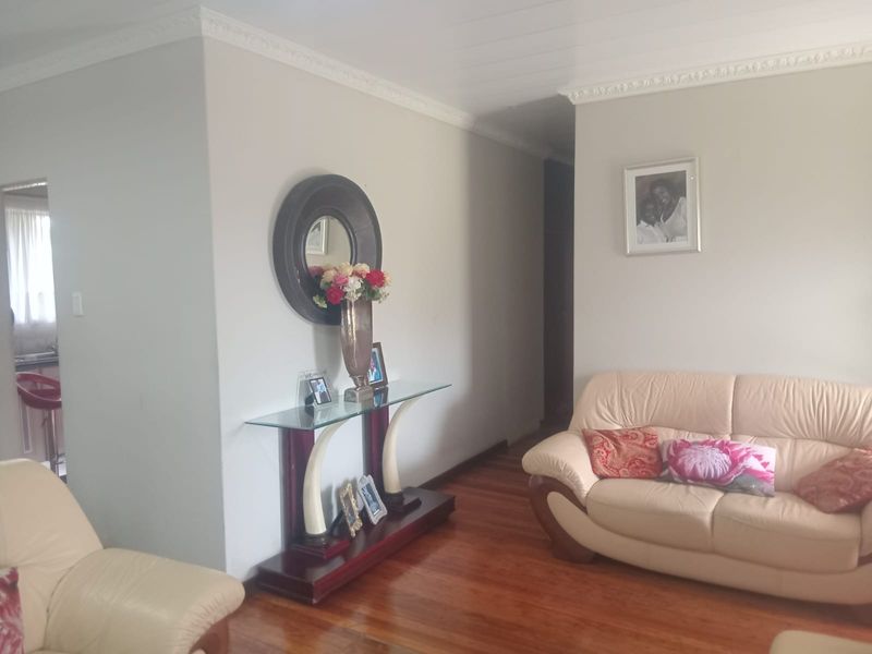 A living room featuring polished hardwood flooring and decorative ceiling cornicing, providing a neutral base for interior design.