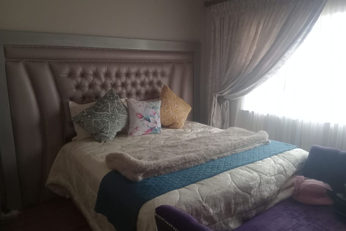A well-lit bedroom featuring laminate flooring and window treatments, providing a comfortable and functional sleeping space.
