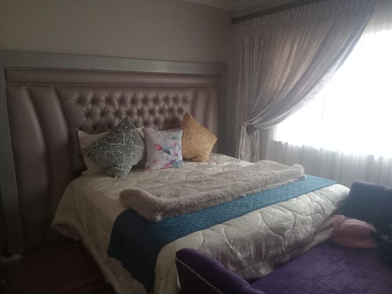 A well-lit bedroom featuring laminate flooring and window treatments, providing a comfortable and functional sleeping space.