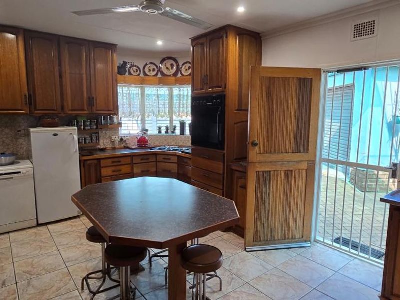 A functional kitchen featuring wooden cabinetry, tiled flooring, a built-in oven, and direct access to the exterior through a security gate.
