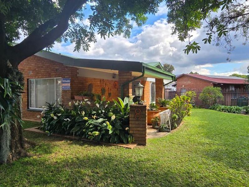 A charming brick-faced house featuring a covered front patio, well-maintained garden, and paved driveway, offering a welcoming street appeal.