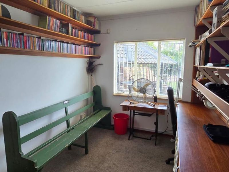 A functional home office featuring extensive built-in wooden shelving and a fitted desk, providing ample storage and workspace.