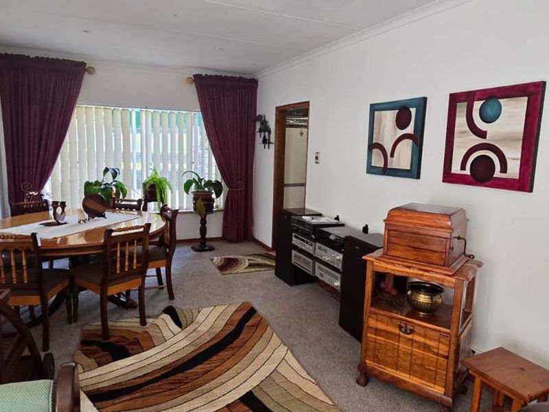 A dining room featuring carpeted flooring, vertical blinds, and coving, providing a functional space for family meals.