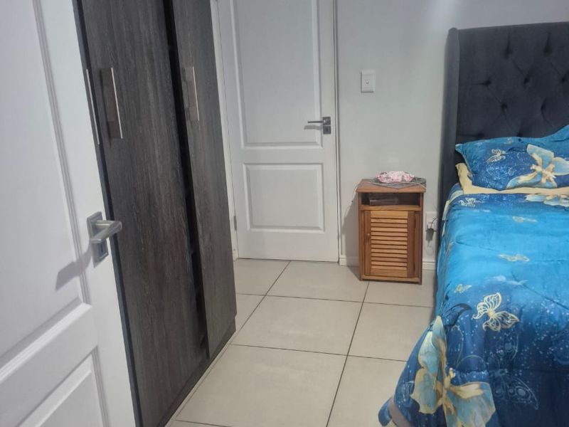 A bedroom featuring neutral tiled flooring and a dark wood-finish built-in wardrobe.