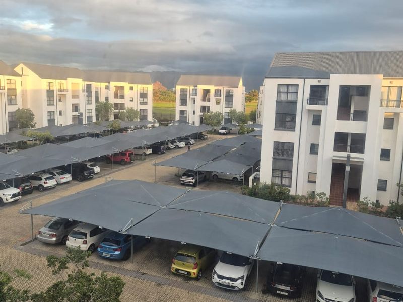 An elevated view of an apartment complex featuring paved parking areas with installed shade cloth carports and multi-story residential buildings.