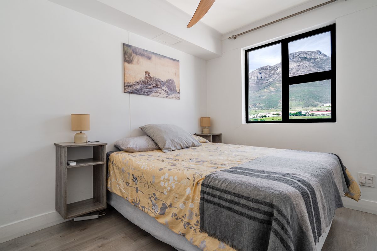 A well-maintained bedroom featuring laminate flooring, a ceiling fan, and a large window offering scenic mountain views.