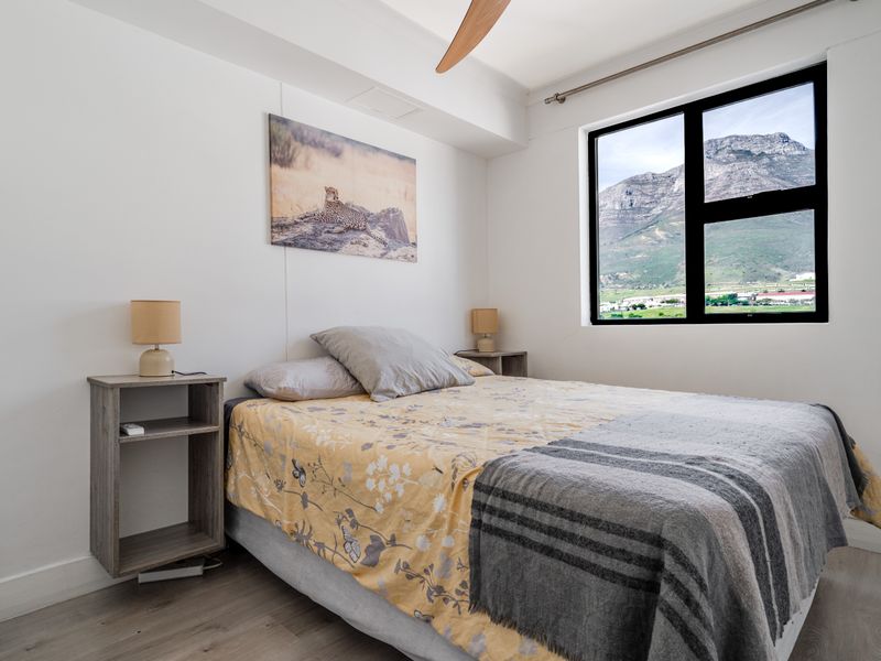 A well-maintained bedroom featuring laminate flooring, a ceiling fan, and a large window offering scenic mountain views.