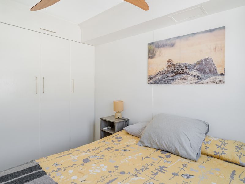 A well-maintained bedroom featuring a large built-in wardrobe and a ceiling fan, providing functional storage and climate control.