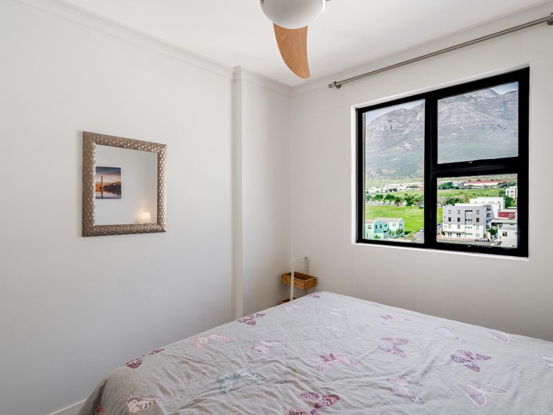 A bright bedroom featuring a ceiling fan and a large window with scenic mountain views.