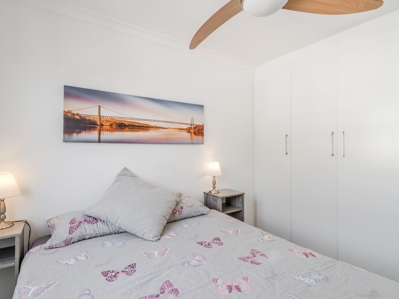 A well-maintained bedroom featuring a built-in wardrobe and a modern ceiling fan, offering a clean and functional living space.