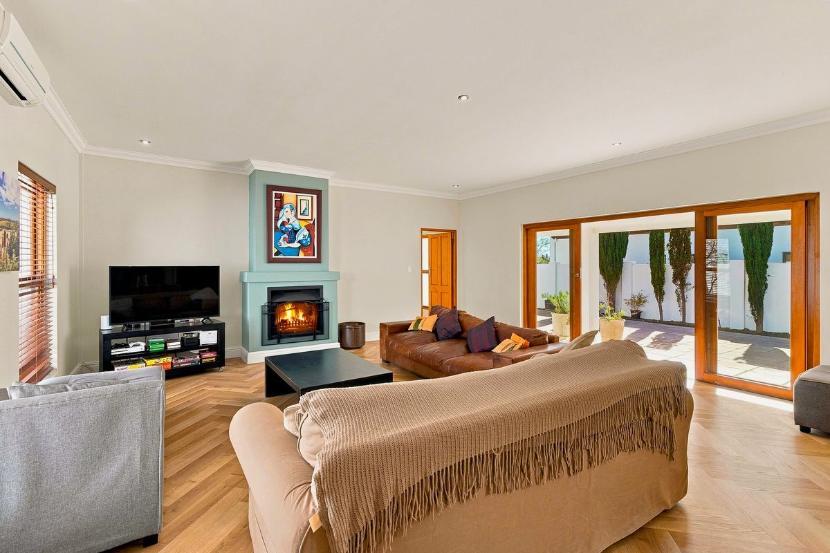 Spacious living room featuring herringbone timber flooring, a feature fireplace, and large sliding glass doors providing seamless access to the outdoor patio area.