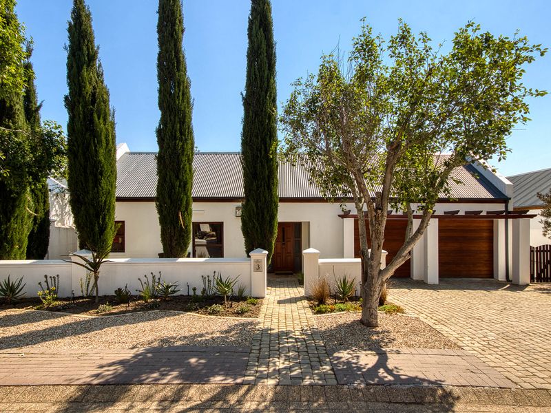 A well-maintained front facade featuring a corrugated metal roof, double timber garage doors, and a paved driveway with established landscaping.