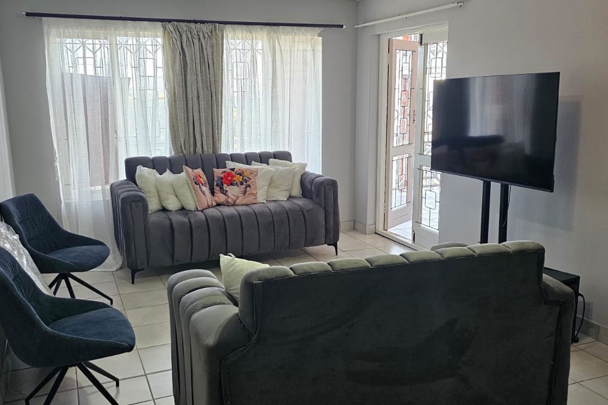 A living room featuring tiled flooring and direct access to an outdoor area through a security gate.