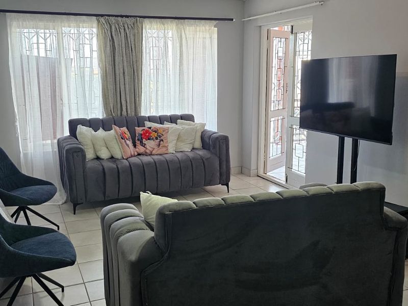 A living room featuring tiled flooring and direct access to an outdoor area through a security gate.