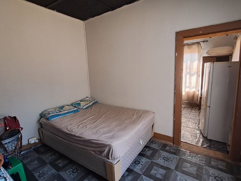 A bedroom featuring tiled flooring and a timber door frame leading to an adjacent space, requiring cosmetic updates and maintenance.
