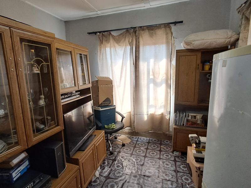 A living area featuring a curtain rod and worn flooring, requiring cosmetic updates to improve the overall condition and appeal of the space.