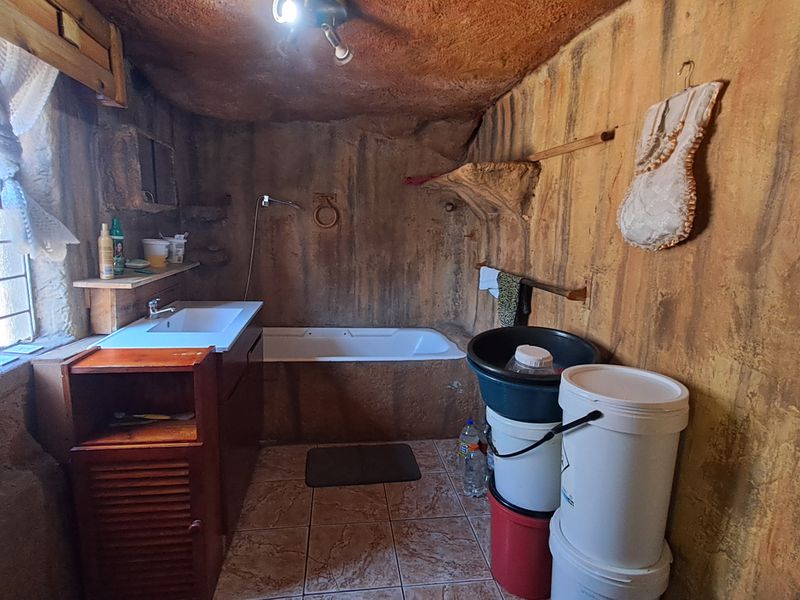 A rustic-style bathroom featuring a built-in bathtub, vanity sink, and unique textured wall finishes with tiled flooring.