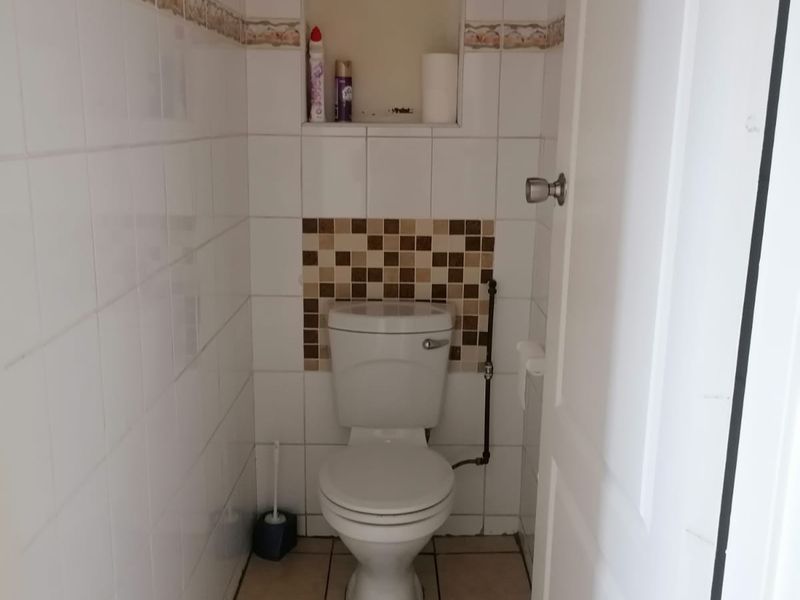 A compact bathroom featuring tiled walls and flooring, a standard toilet, and a recessed wall niche for storage.