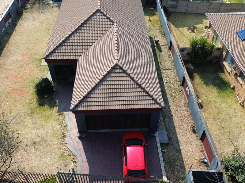 Aerial view of a residential property featuring a tiled roof, paved driveway, and surrounding boundary walls.