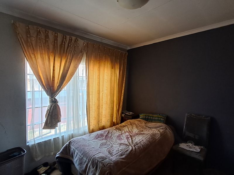 A bedroom featuring a window with curtains and dark painted walls, requiring cosmetic updates to improve the overall condition and appeal.