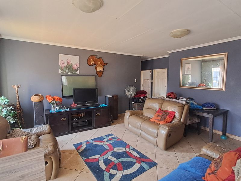 A living room featuring tiled flooring and dark-painted walls, offering a functional space with potential for cosmetic updates and modernization.