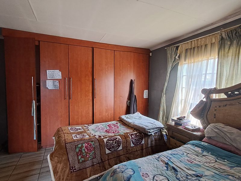 A bedroom featuring built-in wooden cupboards and tiled flooring, offering a functional space with potential for cosmetic updates to modernize the interior finishes.
