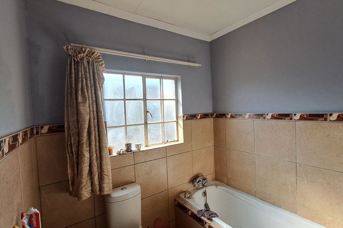 A dated bathroom featuring a standard bathtub, toilet, and partial wall tiling, offering potential for a modern renovation.
