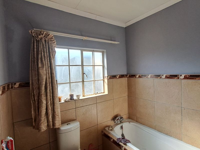 A dated bathroom featuring a standard bathtub, toilet, and partial wall tiling, offering potential for a modern renovation.