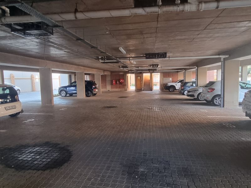 Covered basement parking area with concrete structure, paved flooring, and multiple designated parking bays.