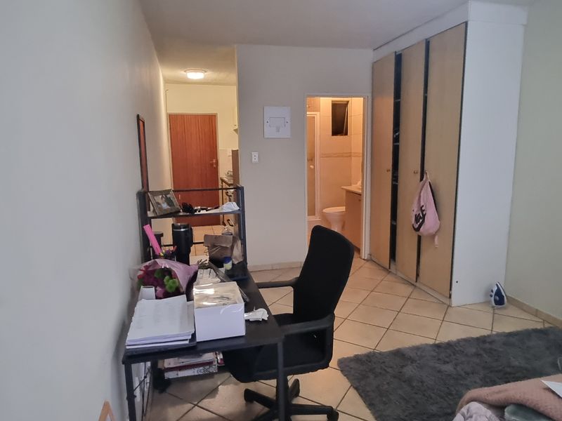 A bedroom featuring built-in cupboards, tiled flooring, and direct access to an en-suite bathroom.