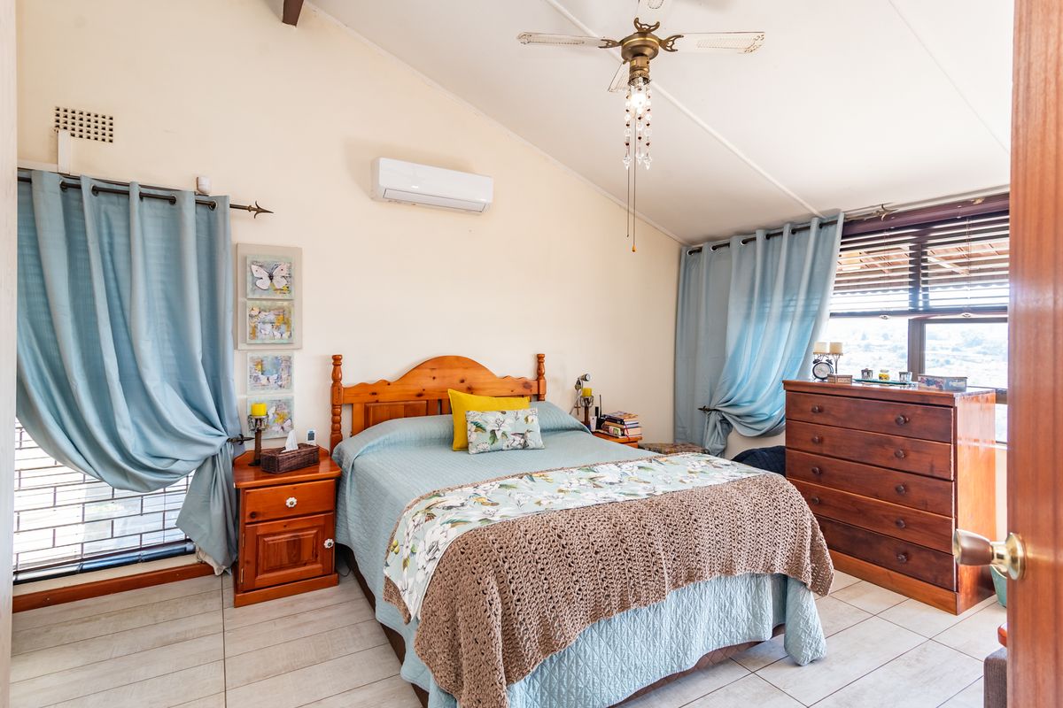 A bedroom featuring a vaulted ceiling, tiled flooring, a ceiling fan, and a wall-mounted split-system air conditioner.