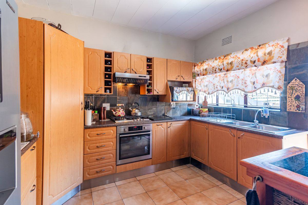 A functional kitchen featuring wooden cabinetry, built-in oven, gas hob, and tiled splashbacks, offering a classic layout with ample storage space.