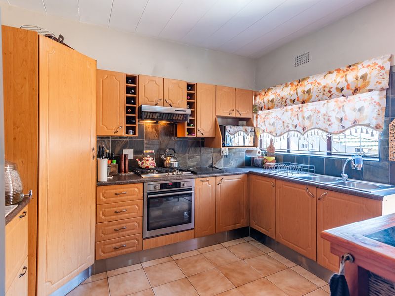 A functional kitchen featuring wooden cabinetry, built-in oven, gas hob, and tiled splashbacks, offering a classic layout with ample storage space.