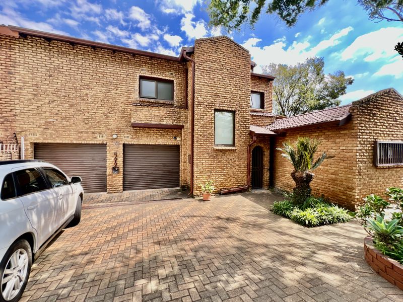 Front elevation of a double-story brick house featuring a paved driveway, double garage, and established garden entrance.