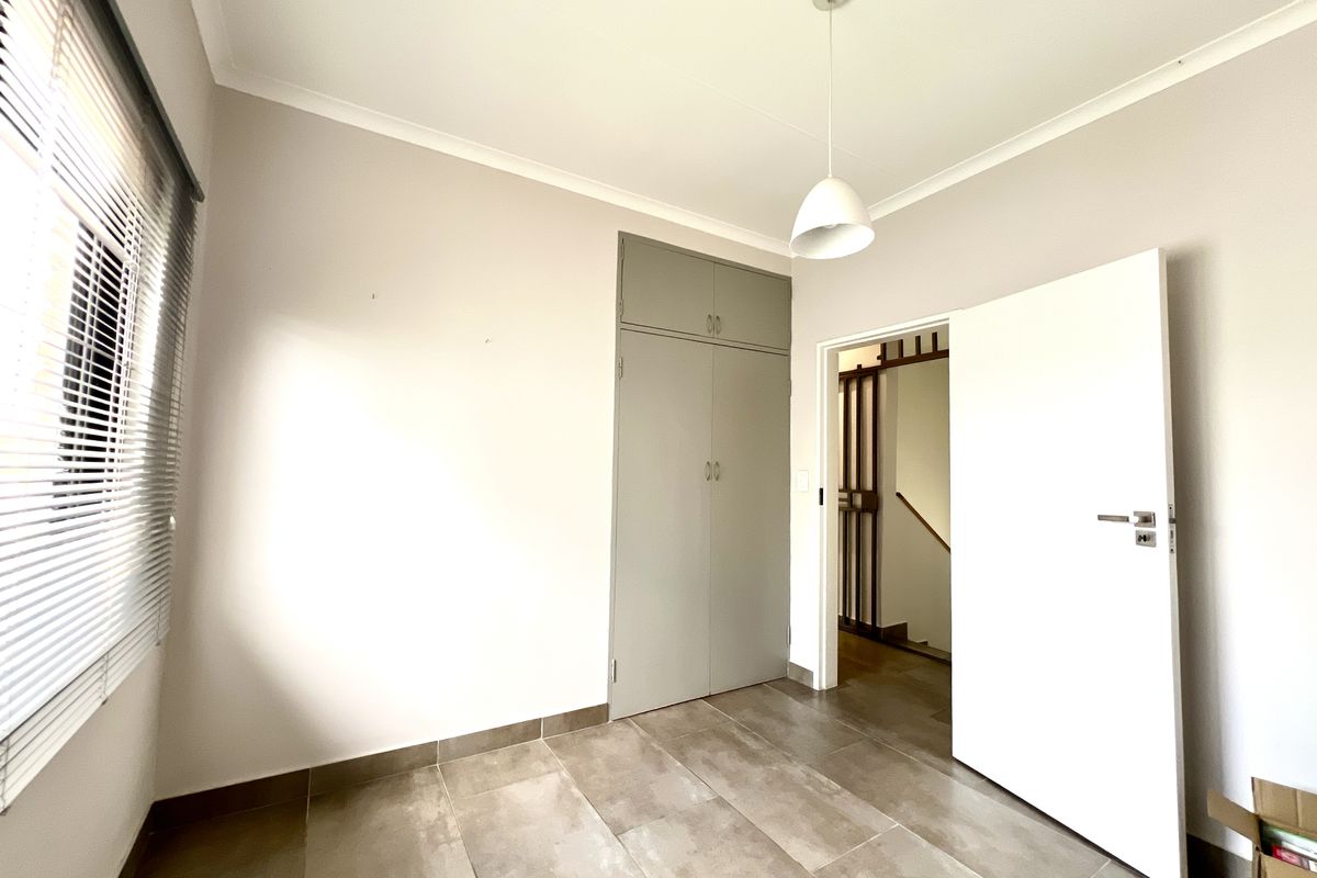 A bright, empty bedroom featuring neutral walls, tiled flooring, and built-in cupboards, offering a clean and versatile space ready for personalization.
