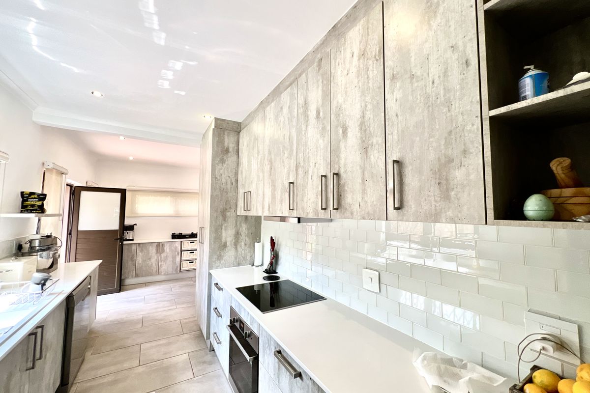 Modern kitchen featuring light wood-grain cabinetry, stone countertops, subway tile backsplash, and integrated appliances with a clean, contemporary aesthetic.