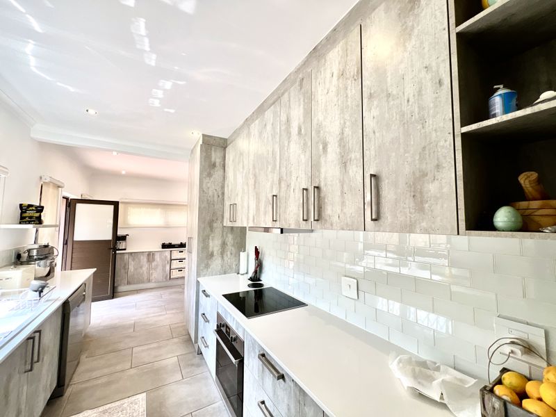 Modern kitchen featuring light wood-grain cabinetry, stone countertops, subway tile backsplash, and integrated appliances with a clean, contemporary aesthetic.
