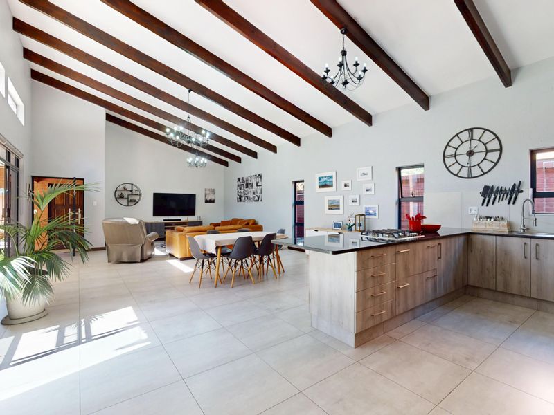 Spacious open-plan living area featuring exposed timber beams, a modern kitchen with island, and large sliding doors leading to the exterior.