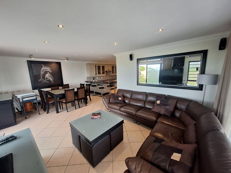 Spacious open-plan living and dining area featuring tiled floors, recessed lighting, and a modern kitchen with granite countertops and breakfast bar.