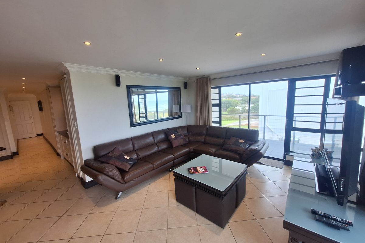 Spacious living room featuring tiled flooring, recessed lighting, and large sliding glass doors providing access to the balcony and natural light.