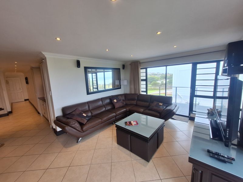 Spacious living room featuring tiled flooring, recessed lighting, and large sliding glass doors providing access to the balcony and natural light.