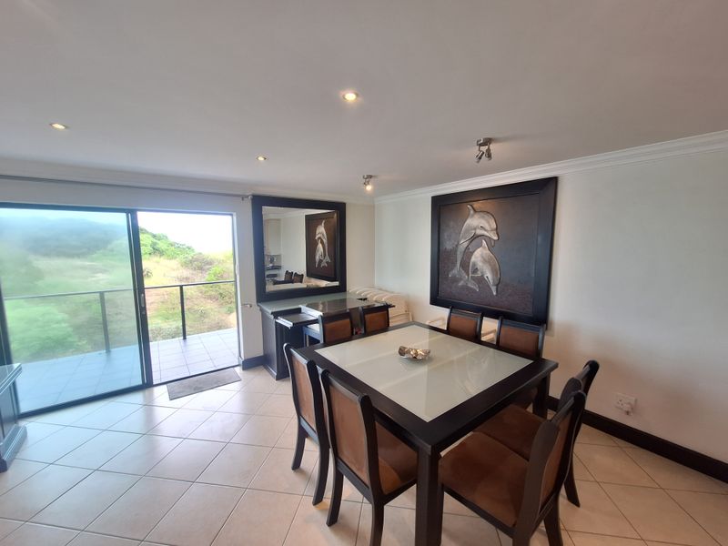 A bright dining area featuring tiled flooring, recessed lighting, and a large sliding glass door providing access to an outdoor balcony.
