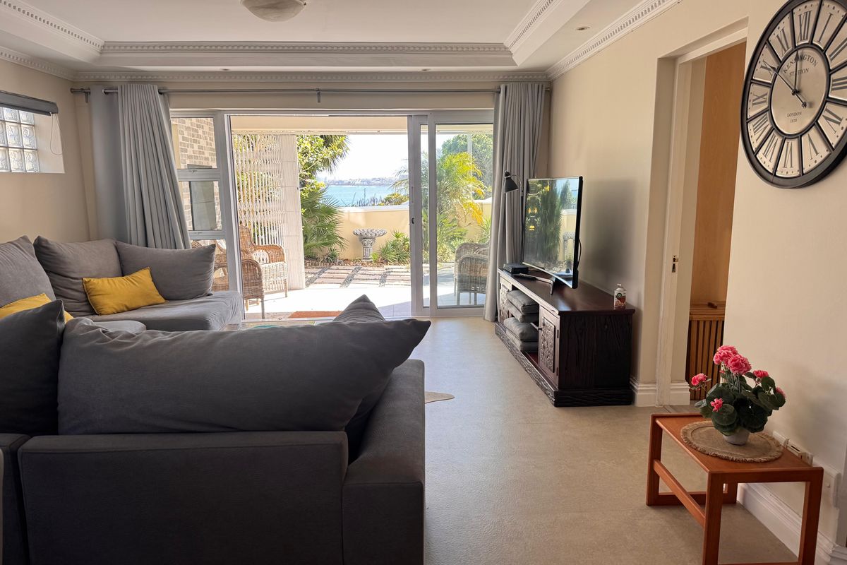 Spacious living room featuring crown molding, tiled floors, and large sliding glass doors that open to a patio with scenic views.
