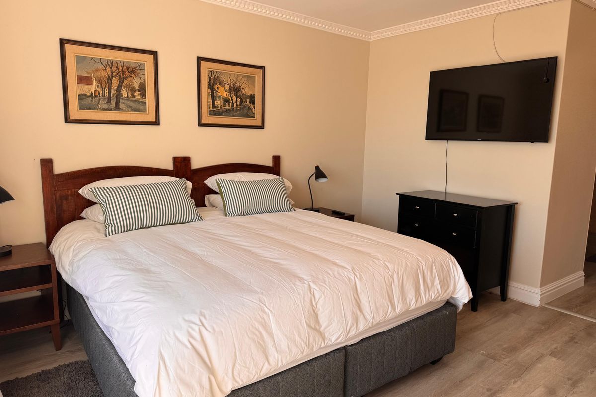 A well-maintained bedroom featuring crown molding, laminate flooring, and a ceiling fan, providing a comfortable and neutral living space.