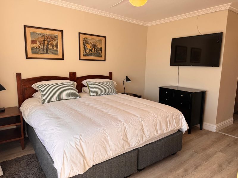A well-maintained bedroom featuring crown molding, laminate flooring, and a ceiling fan, providing a comfortable and neutral living space.