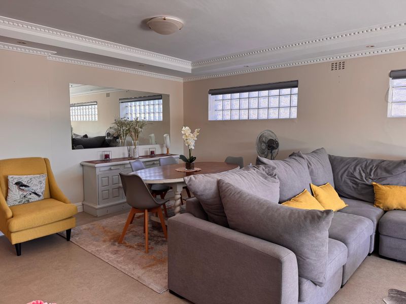 A well-maintained living and dining area featuring decorative crown molding, recessed lighting, and distinctive glass block windows that provide natural light.