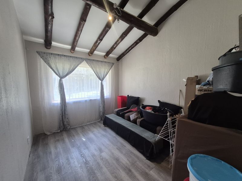 A bedroom featuring exposed timber ceiling beams and modern laminate flooring, offering a rustic yet contemporary aesthetic.