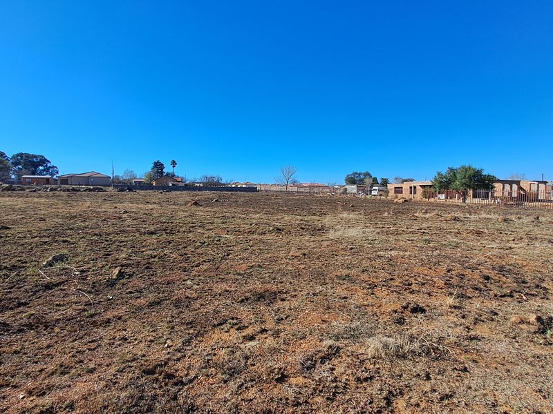 A wide-angle view of a vacant residential plot featuring cleared ground and perimeter fencing, suitable for new development.