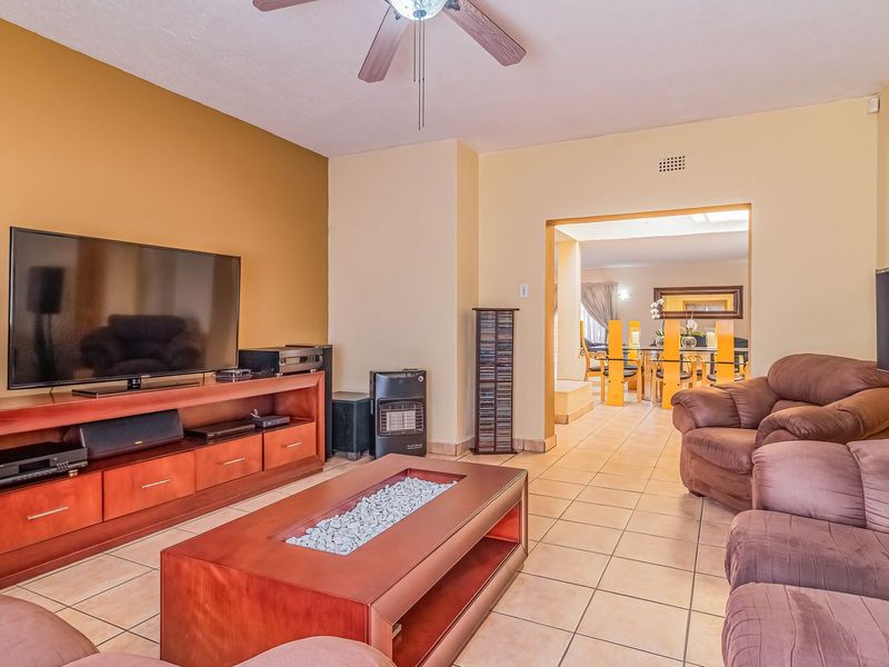 Spacious living room featuring tiled flooring and a ceiling fan, with an open-plan flow leading into the adjacent dining area.